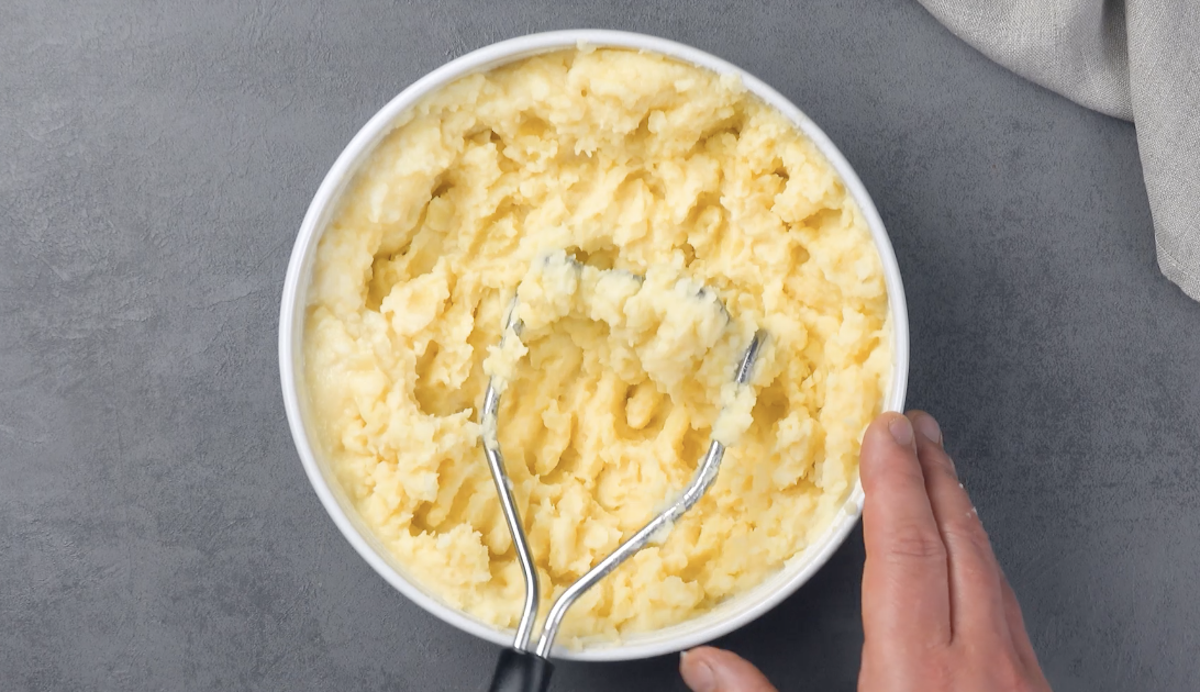 purée de pommes de terre dans un saladier avec un presse purée