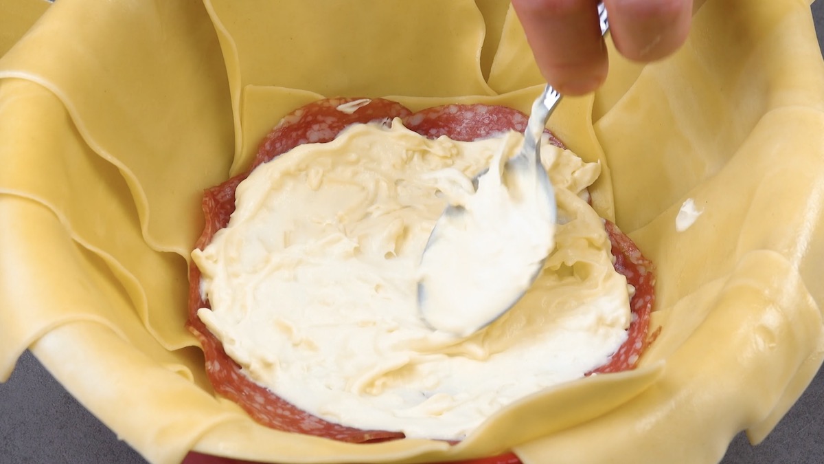 de la sauce béchamel étalée sur le salami déposé sur les feuilles de lasagnes