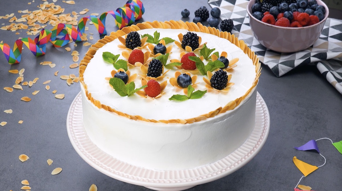 gâteau décoré avec des baies, des amandes et des feuilles de menthe