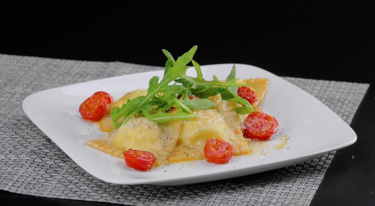 raviolis sur assiette accompagnés de roquette et de tomates